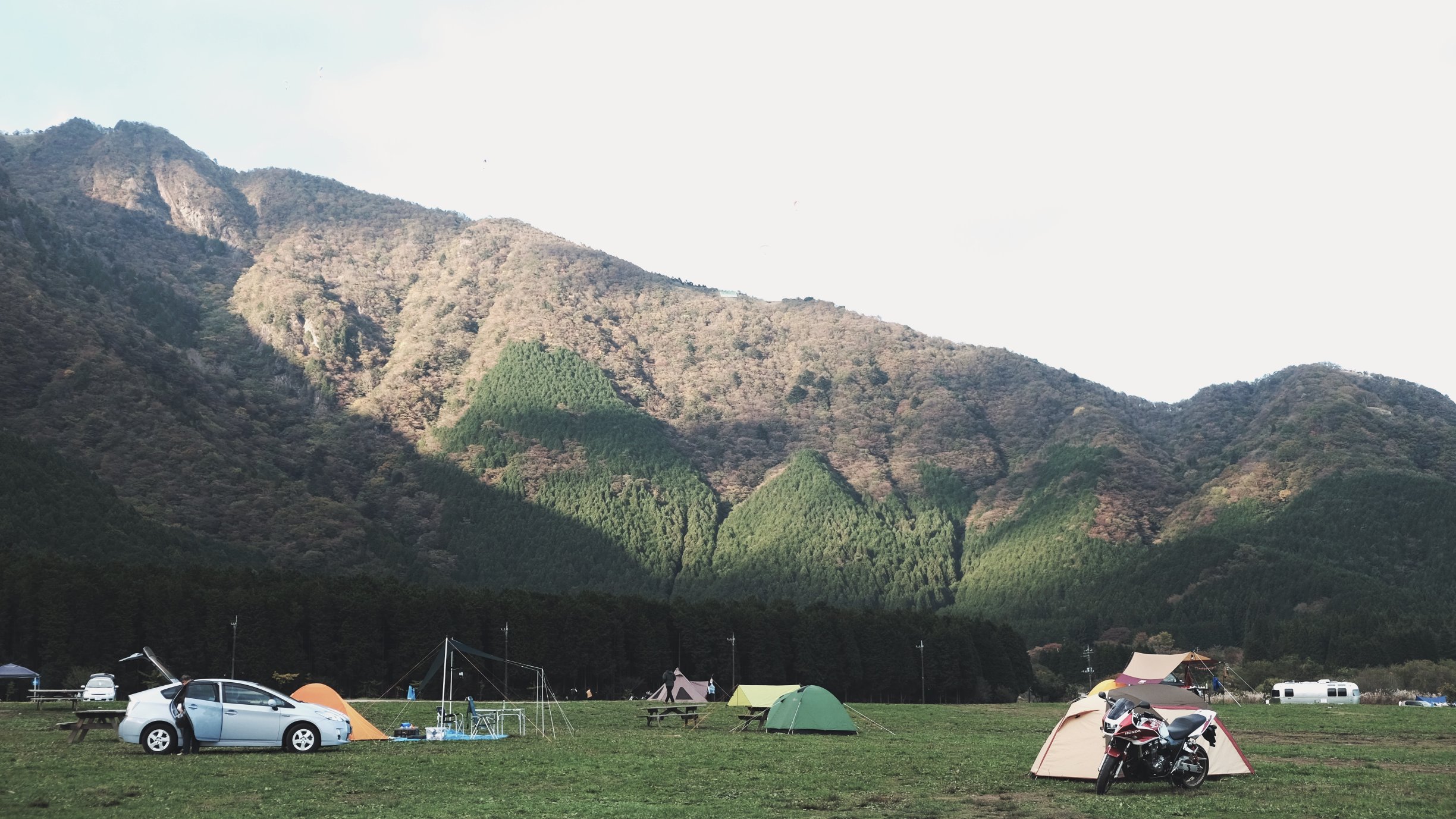 Tents and vehicles at the base of a scenic mountain range, reflecting the calm reliability and local support behind trusted managed IT services.