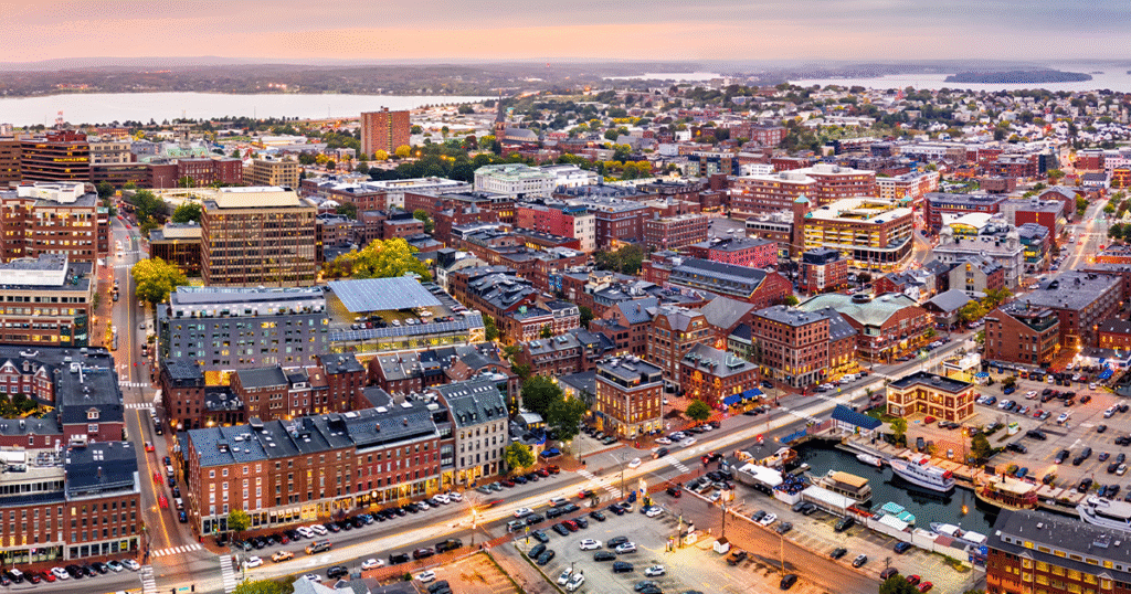 Aerial view of downtown Auburn, Maine at sunset, showcasing city lights, historic buildings, and the vibrant community supported by managed IT services.