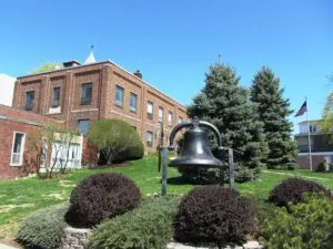 Landscaped public area in Brewer featuring a historic bell and red-brick building, symbolizing the town’s balance of tradition and modern managed IT support.