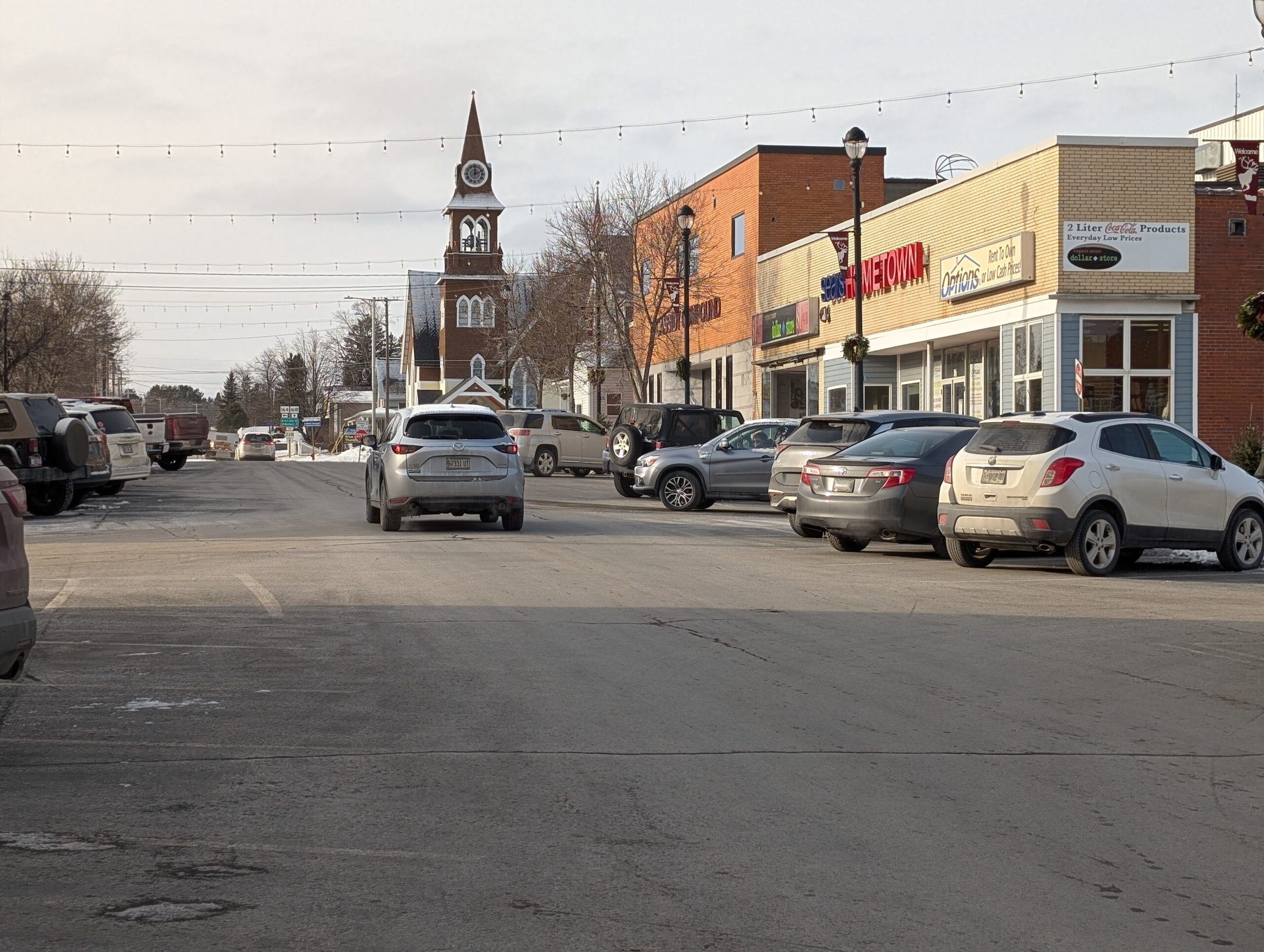 Downtown Caribou, Maine, on a winter day with parked cars, local shops, and the historic clock tower in view.