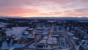 A winter sunrise over Caribou, Maine, showing rooftops dusted with snow and a soft pink sky above the quiet northern town.