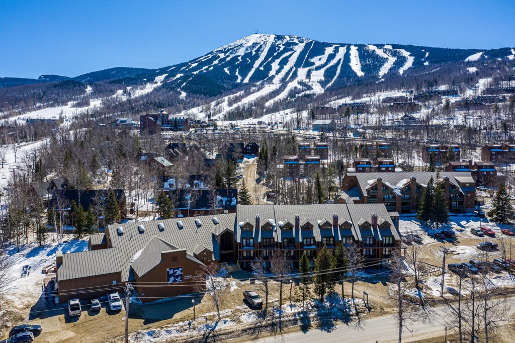 Winter aerial view of Carrabassett Valley with Sugarloaf Mountain in the background, showcasing the remote Maine community that benefits from managed IT services to stay connected and resilient.