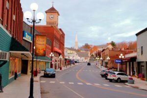 Downtown Dexter, Maine on a sunny day with historic red-brick buildings, street lamps, and a clear blue sky lining the main street.