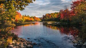 Scenic view of Farmington, Maine’s riverfront in autumn, representing community strength and the growing need for managed IT support in rural towns.