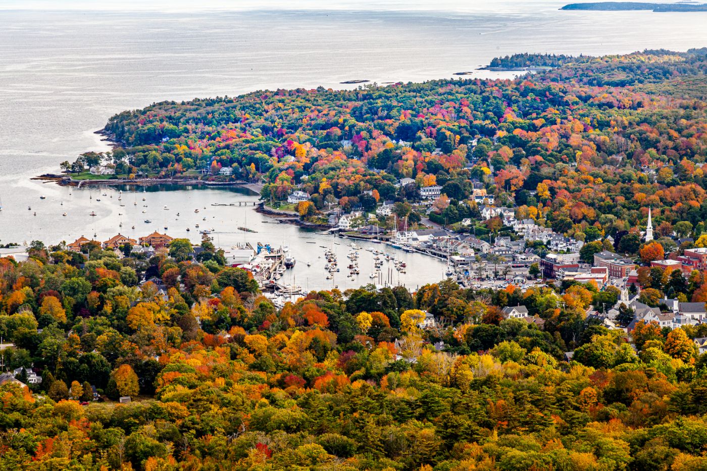 Scenic aerial view of Hampden, Maine in peak autumn, overlooking the Penobscot River with vibrant fall foliage and waterfront homes.