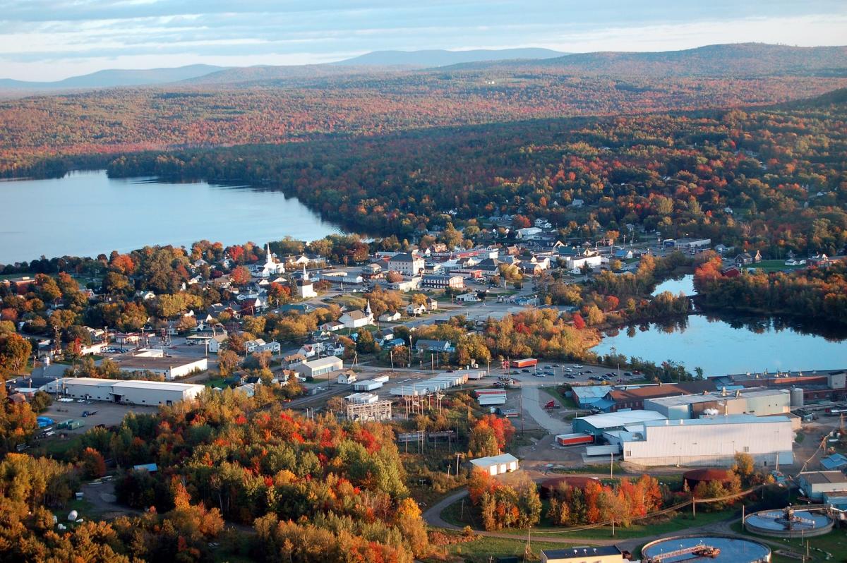 Aerial view of a small Maine town surrounded by fall foliage, where managed IT supports local business operations and community services.