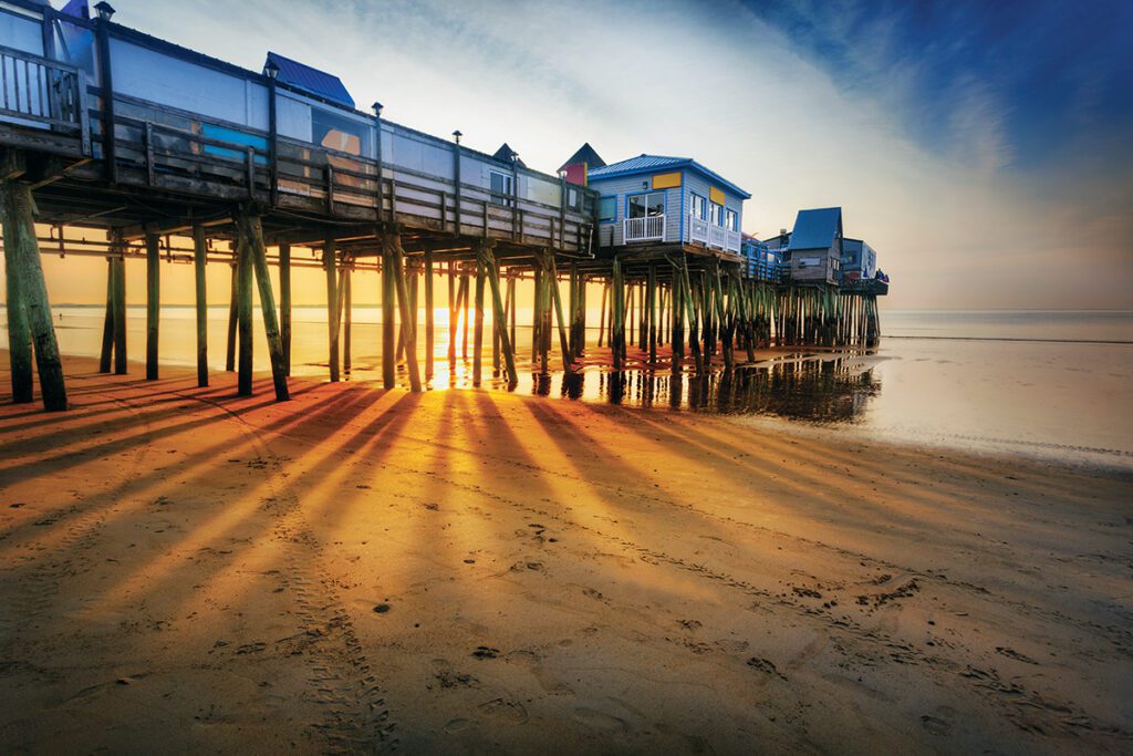 Sunset view of the Old Orchard Beach pier symbolizing the importance of managed IT for seasonal businesses and coastal operations in Maine.