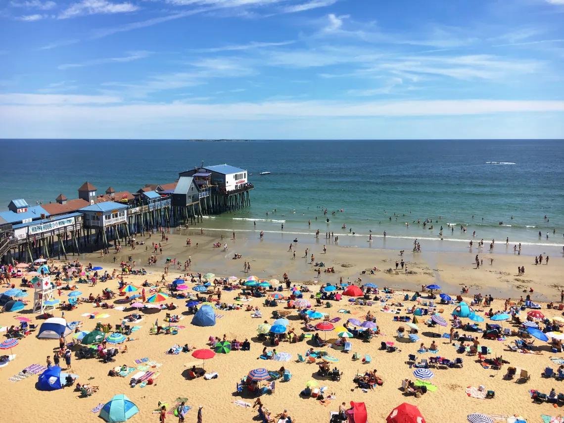 Crowded beach and historic pier at Old Orchard Beach, highlighting the seasonal need for reliable managed IT services to support tourism businesses.