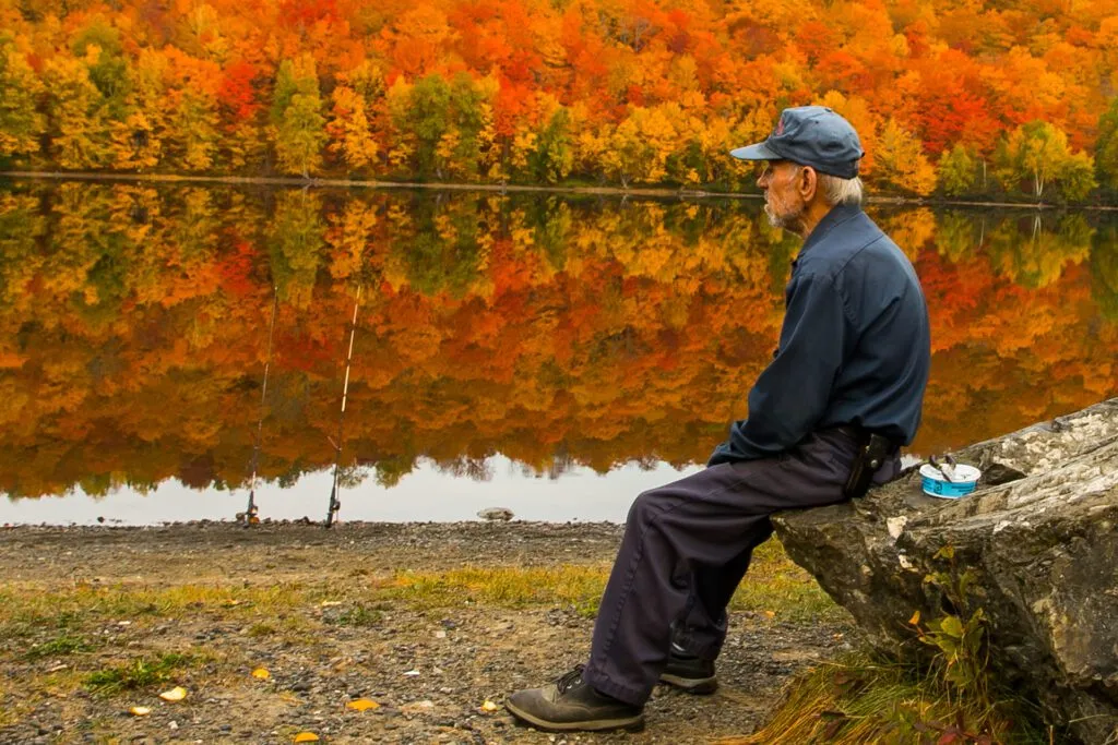 Man fishing by a calm river during autumn in Maine, symbolizing peace of mind supported by reliable managed IT services.