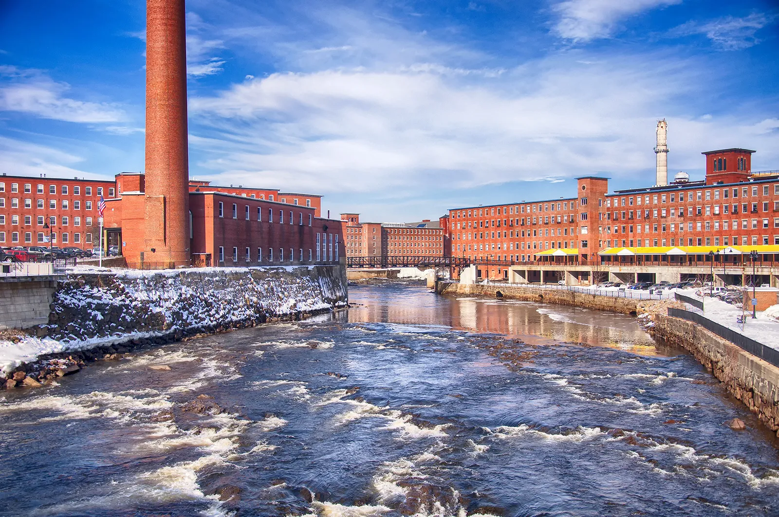 Historic mill buildings along the Saco River in Biddeford, Maine—a revitalized city where local businesses depend on reliable IT services to thrive year-round.