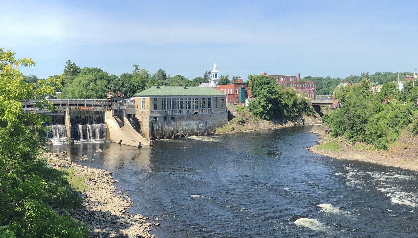 View of the Androscoggin River flowing past Lewiston’s historic downtown, where managed IT services support local government and business continuity.