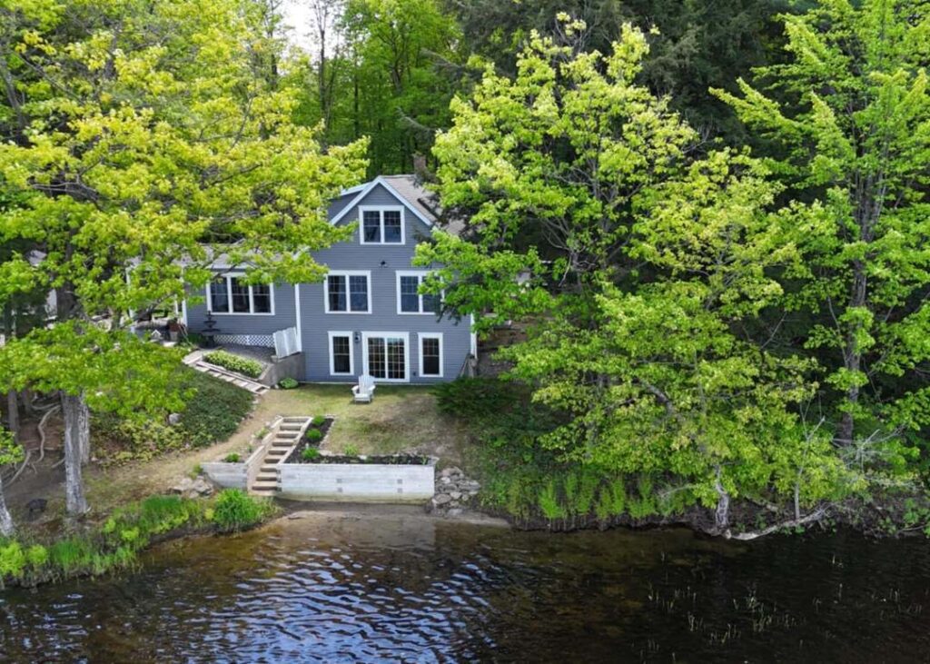 Lakefront home surrounded by dense green trees in Turner, Maine—highlighting the peaceful lifestyle supported by dependable managed IT services behind the scenes.