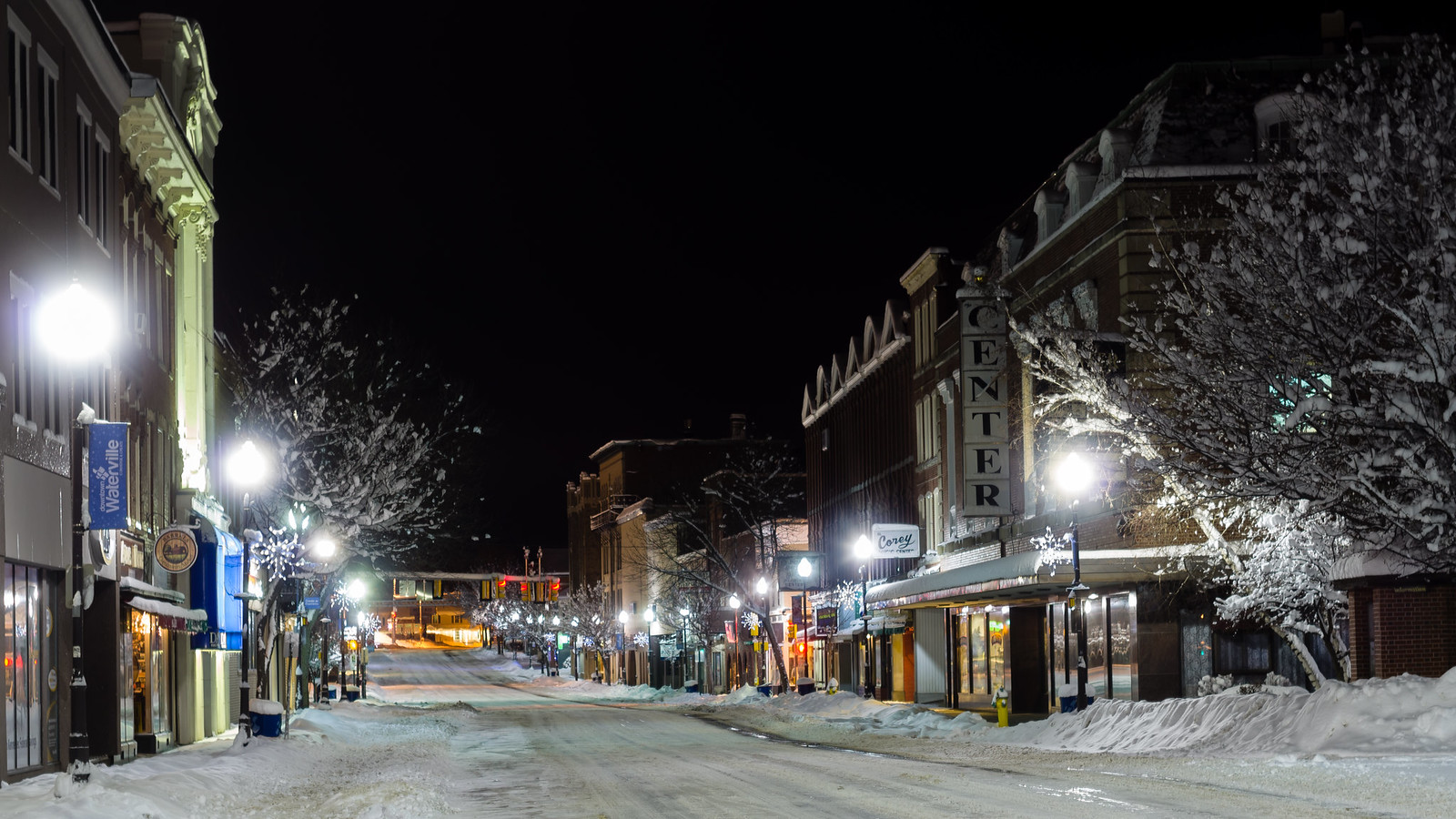 Downtown Waterville, Maine at night with lit storefronts and empty streets, representing the quiet reliability of managed IT services supporting local businesses after hours.